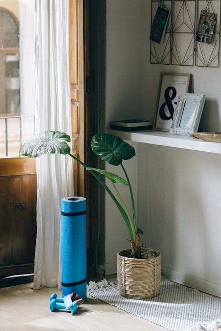 A person working on a laptop at home next to a yoga mat